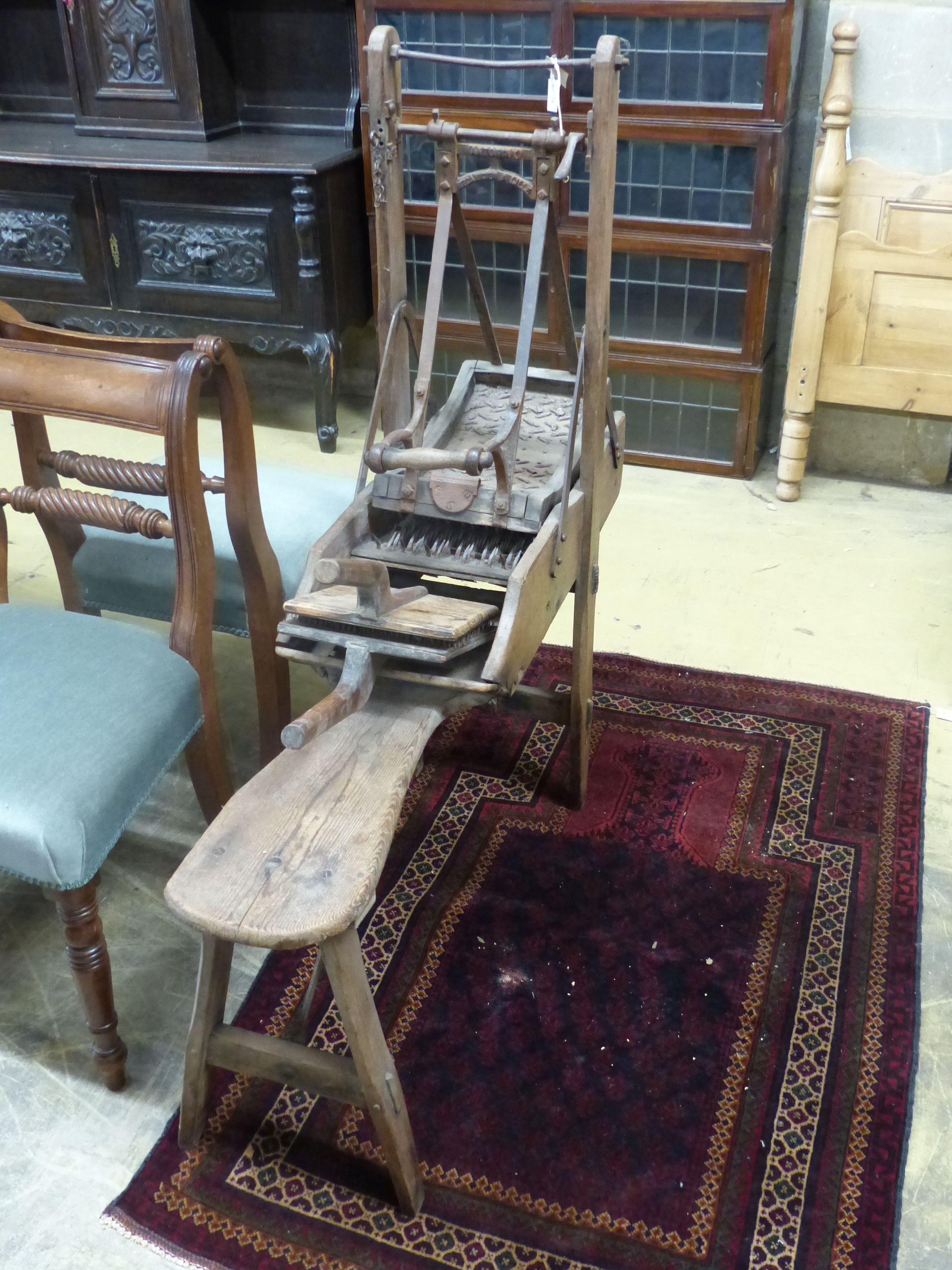 A late 19th century French Provincial (Lille) pine and wrought iron carding machine and two carding combs, length 113cm, height 120cm